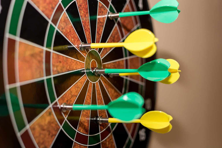 dartboard with green and yellow darts stuck in it