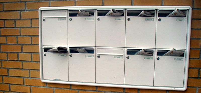 Community mailbox built into the side of a building with mail sticking out of each one