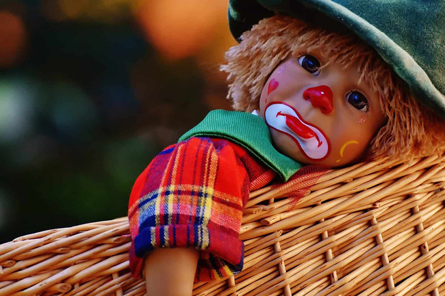 sad and lonely clown doll laying in a basket