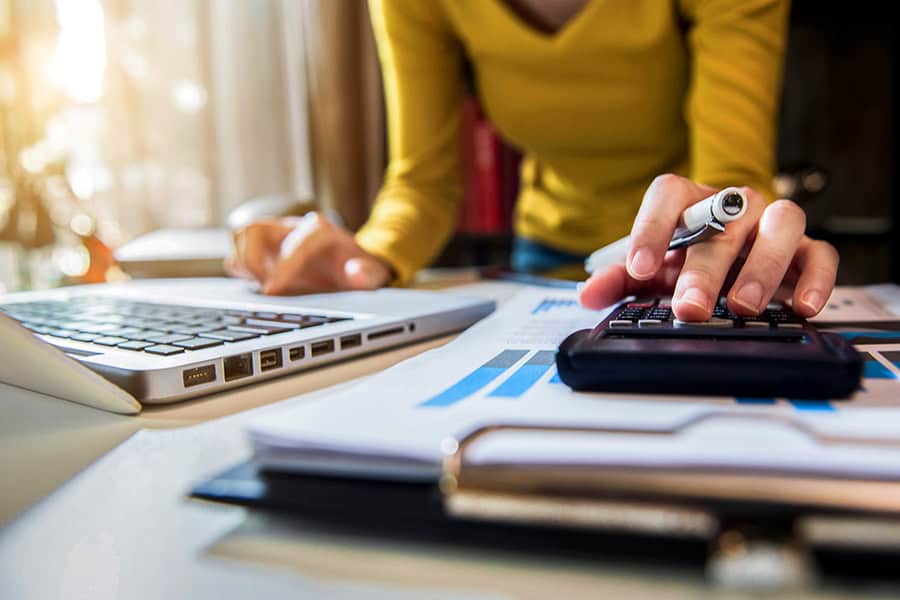 A woman using a calculator to crunch numbers and figure out how much a website should cost