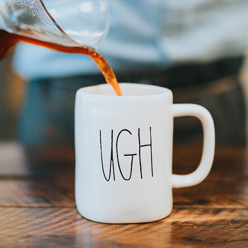 A local business owner pouring coffee into a mug that says ugh, because that's how he is feeling and struggling to come up with blog topics for his business