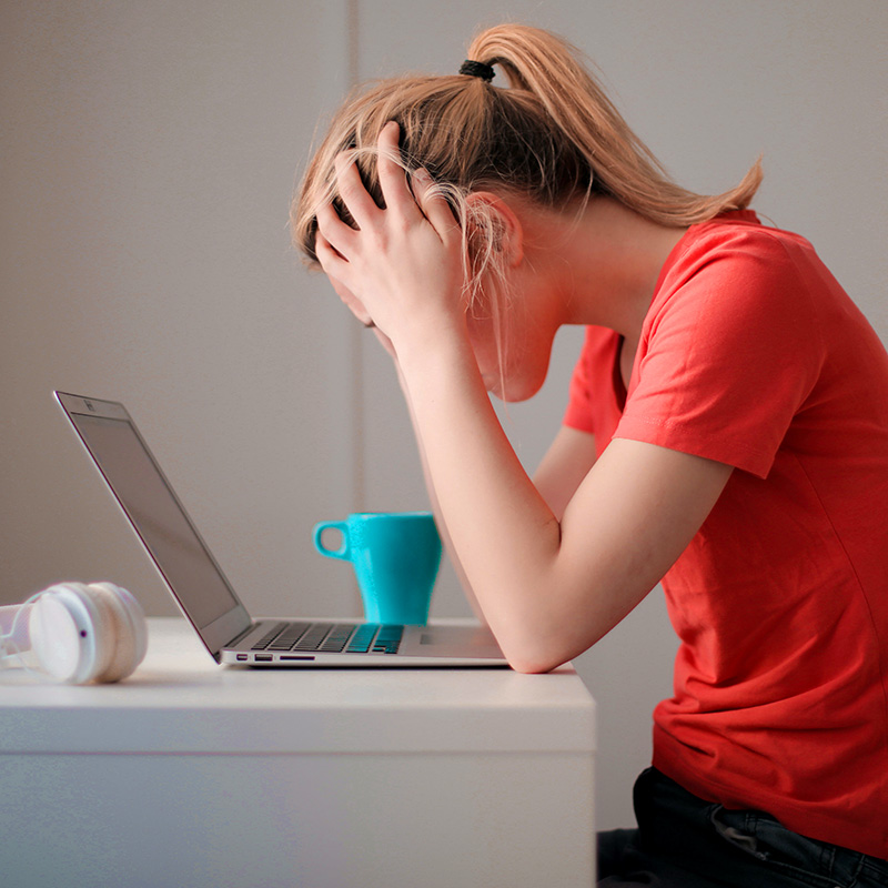 A frustrated woman with her head in her hands because writing website content is hard